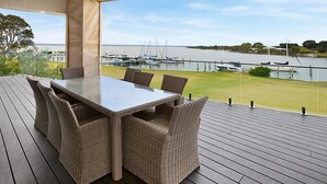 A covered outdoor dining area with a table and chairs, overlooking a marina with boats.