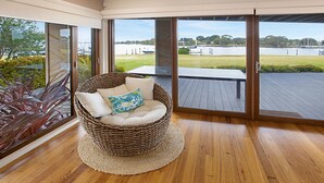 A wicker chair with cushions and a view of a lake through large sliding glass doors.