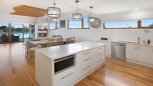 A modern kitchen with a large island, white cabinetry, and a view of the outdoors.
