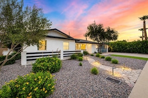 A modern house with a white exterior, a black fence, and a well-maintained garden with various plants and a stone pathway. - Ochenta Oasis| 2 Primarys | Heated Pool & Theater (Scottsdale)