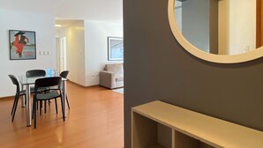 Un salon moderne comprenant un coin repas, un miroir rond et un tableau encadré accroché au mur.