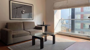Un salon moderne avec un canapé, une table basse en verre et un tableau encadré accroché au mur.
