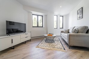 A modern living room with a flat-screen TV, a sofa, and a coffee table. - Solihull Studio • WiFi • NEC • BHX (Solihull)
