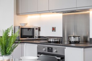 A modern kitchen with stainless steel appliances, a microwave, an oven, and a pot on the stove. - Solihull Studio • WiFi • NEC • BHX (Solihull)