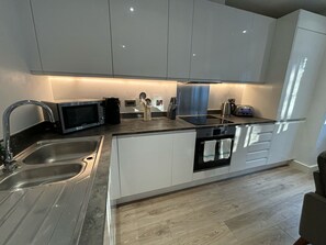 A modern kitchen with stainless steel appliances, a double sink, and white cabinetry. - Solihull Studio • WiFi • NEC • BHX (Solihull)