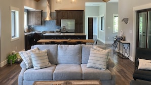 A spacious living room with a grey sofa, wooden coffee table, and a ceiling fan.