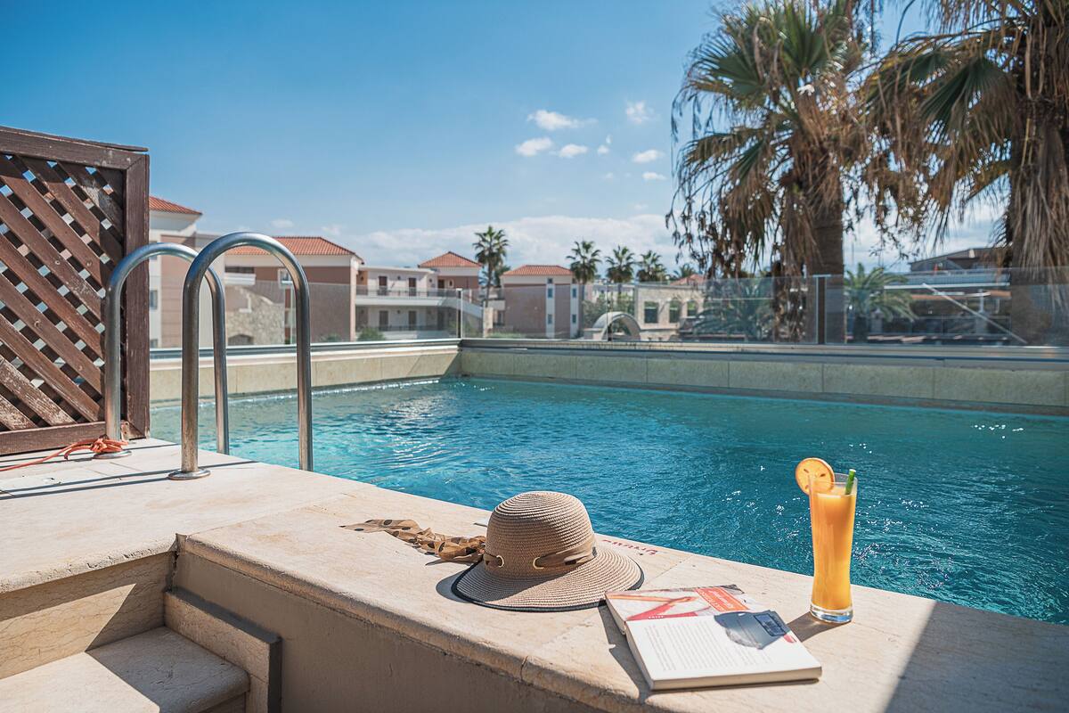 A poolside area with a hat, a drink, and a book on a ledge.