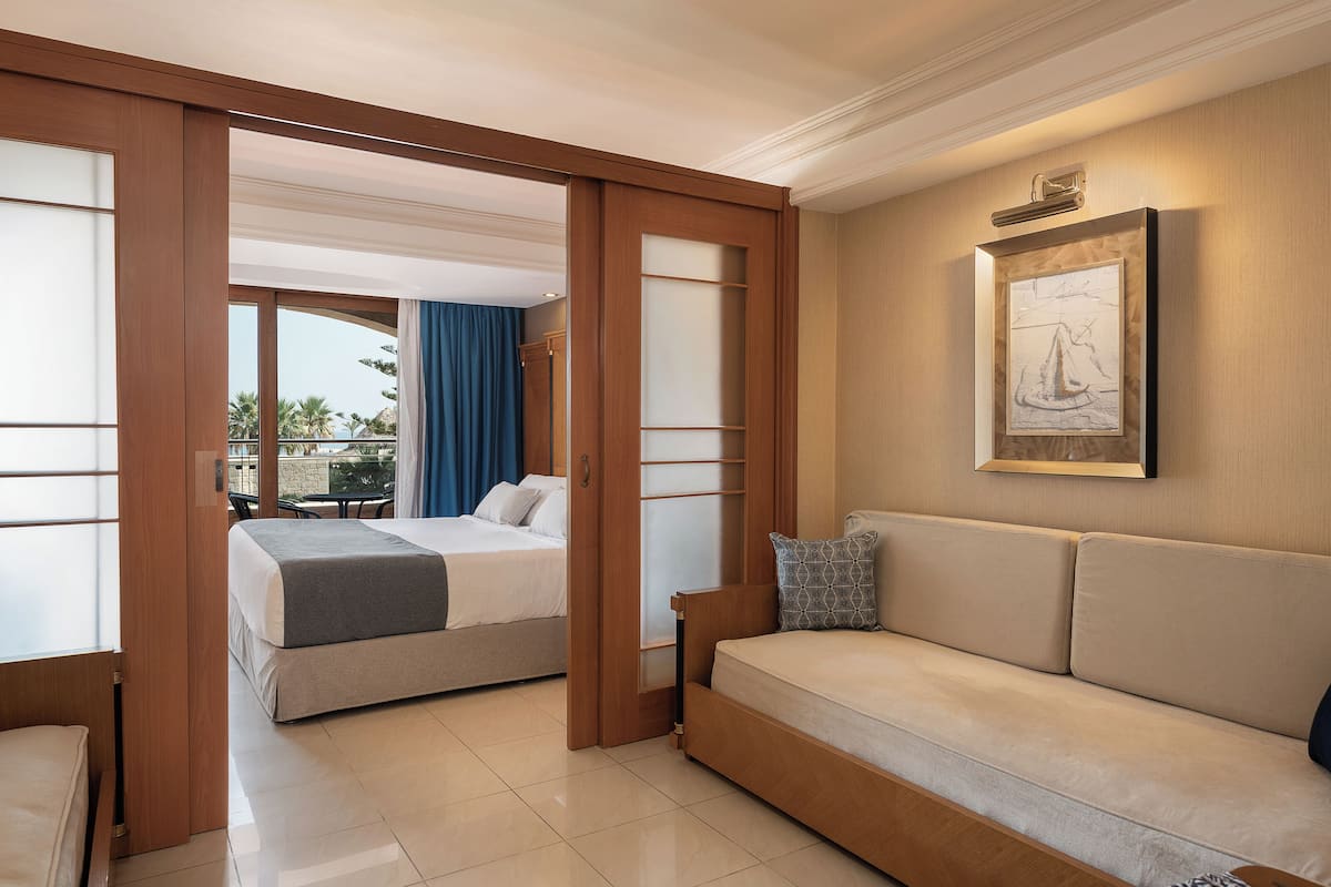 A hotel room with a bed, a sofa, and a large window with curtains.