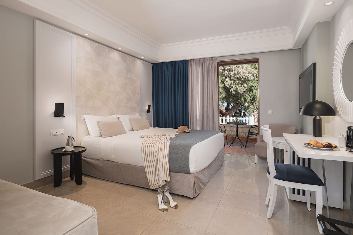 A modern hotel room with a large bed, a desk, and a view of the outdoors.