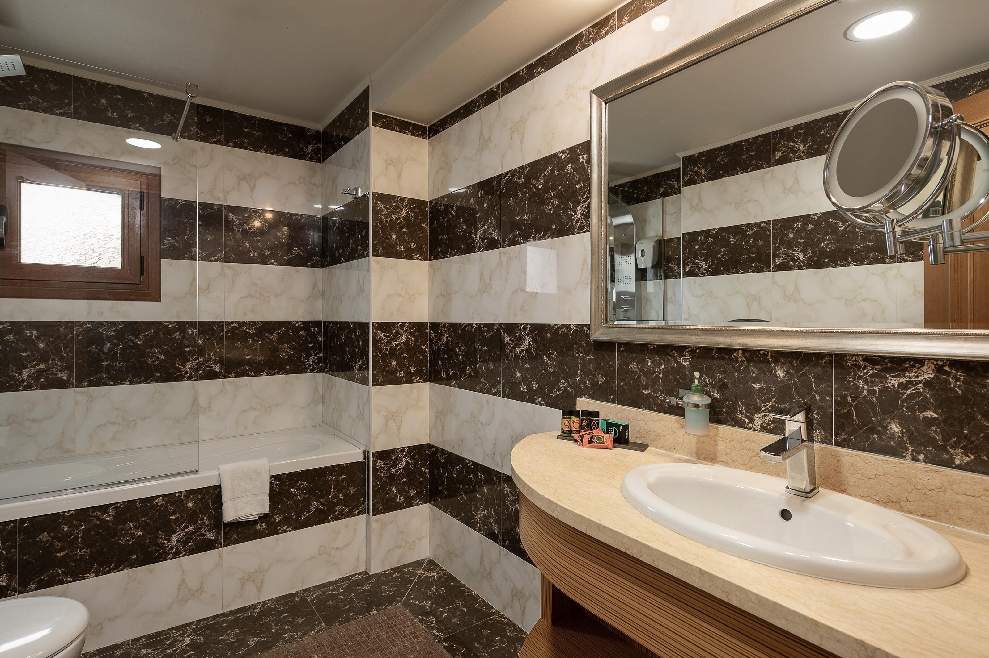 Un baño con una bañera, un lavabo y un espejo grande.