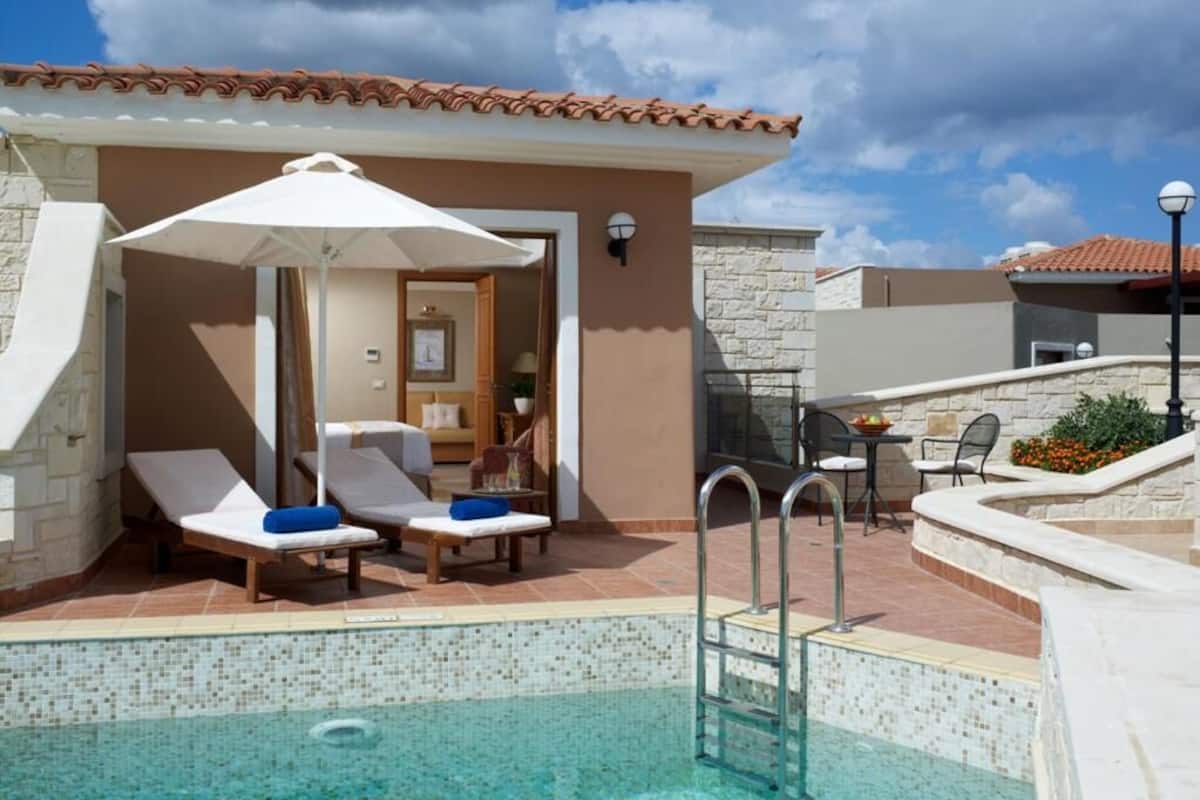A pool area with lounge chairs, a covered seating area, and a staircase leading to an upper level.