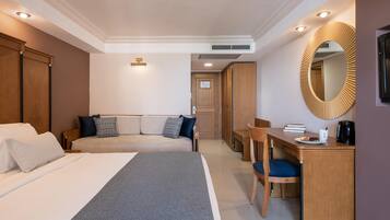 Ein Hotelzimmer mit Bett, Schreibtisch, Sessel, Sofa und Spiegel.