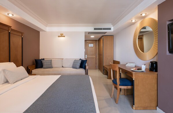 A hotel room with a bed, a desk, a chair, a sofa, and a mirror. - Caldera Creta Paradise (Platanias)