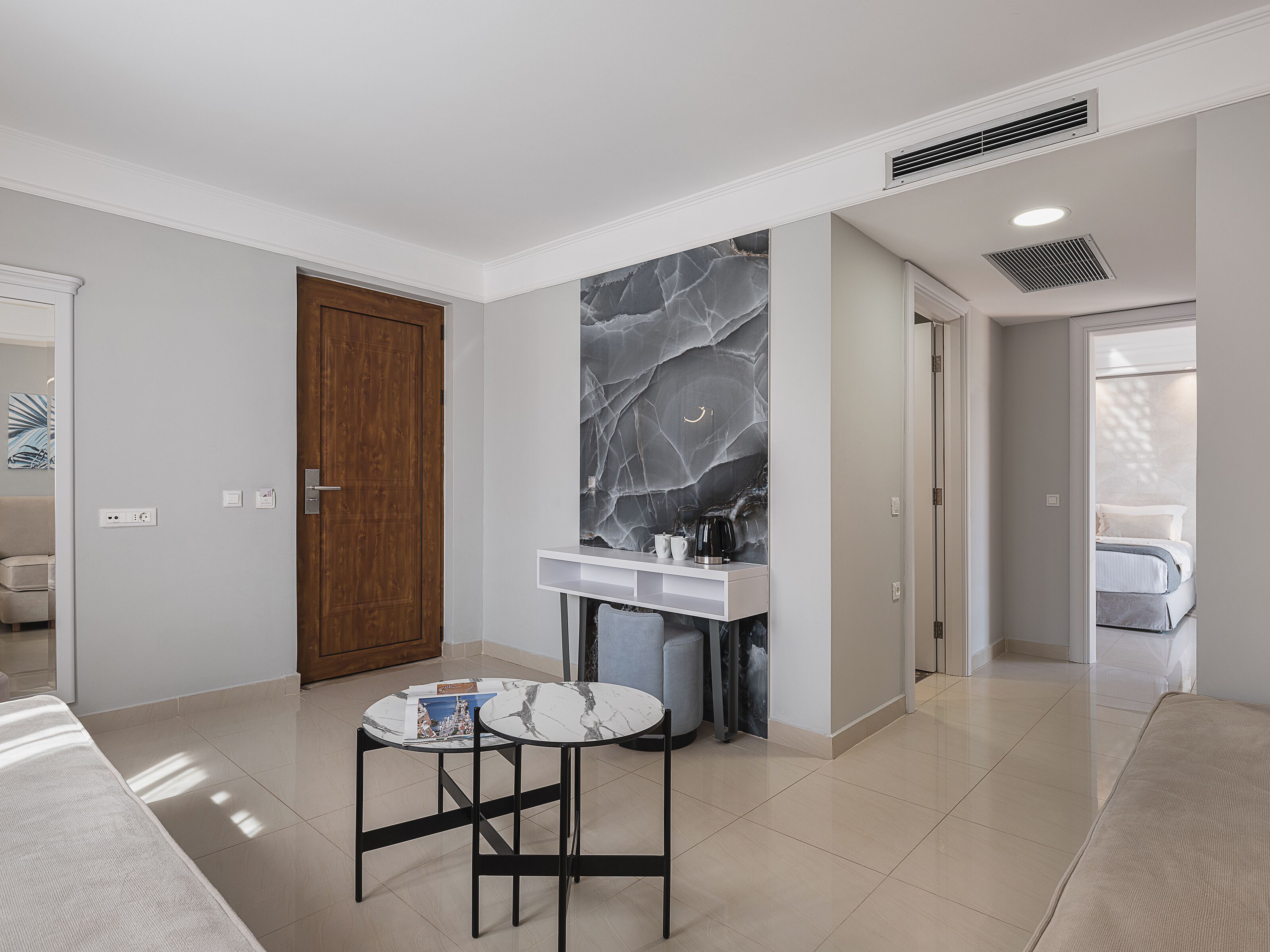 A modern hotel room with a marble accent wall, a small round table, and a bed.