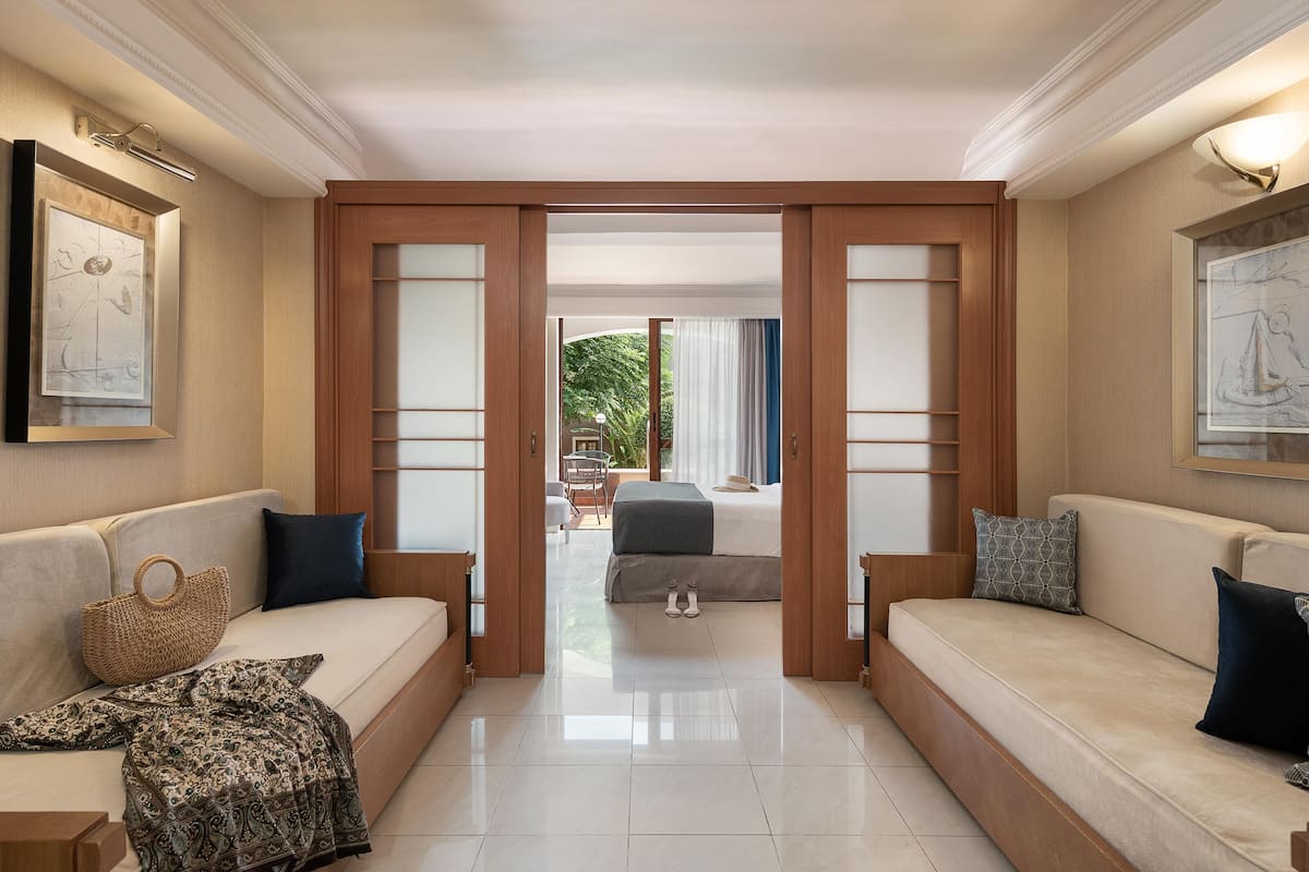 A hotel lobby with a sofa, a woven bag, and a bed in the background.