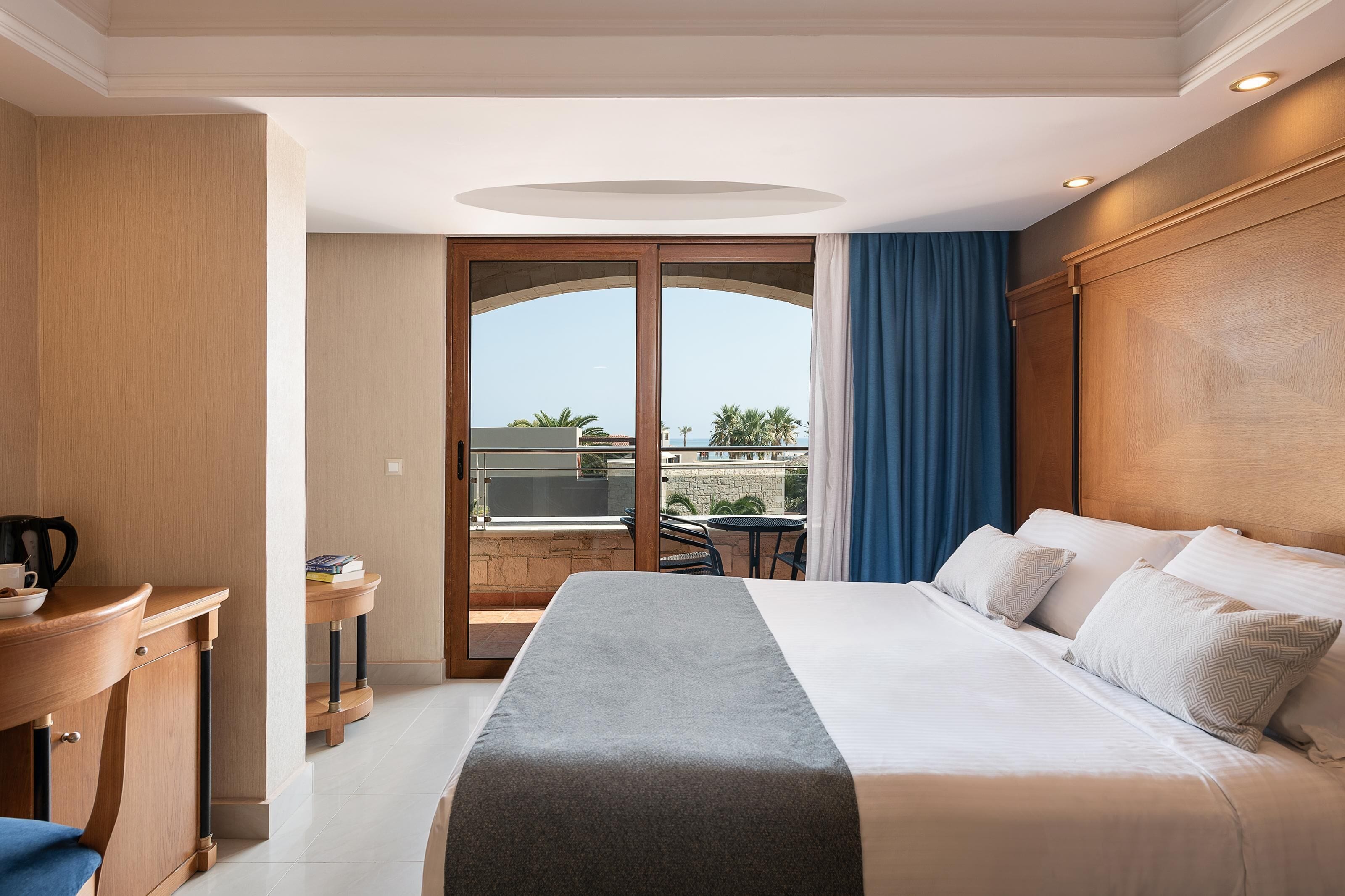 A hotel room with a bed, a desk, and a view of the outside.