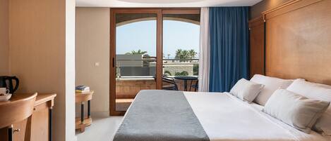 A hotel room with a bed, a desk, and a view of the outside.