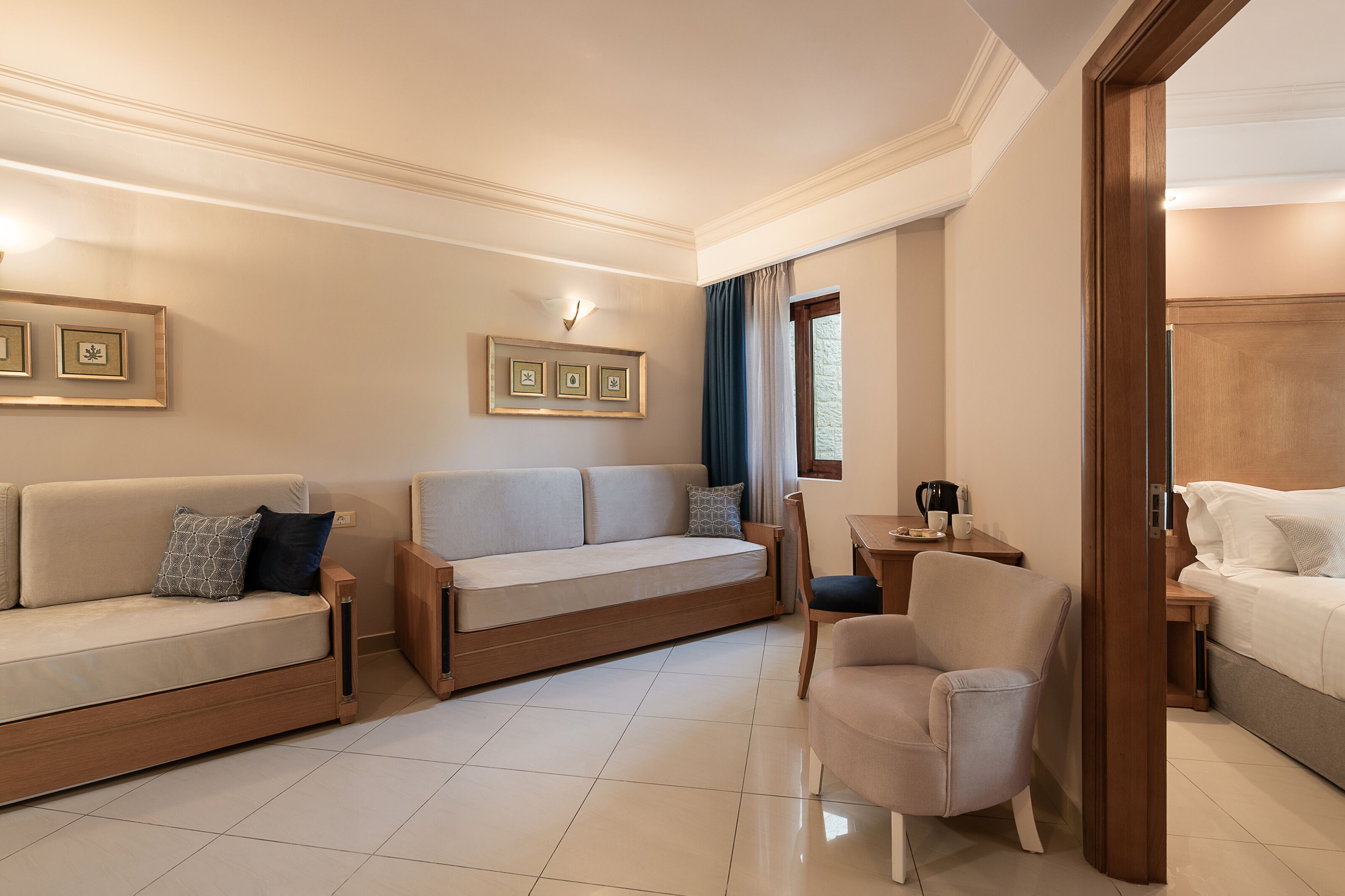 A modern hotel room with a sofa, armchair, and a bed.