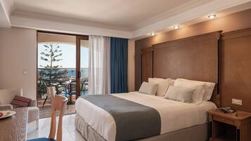 A hotel room with a bed, a desk, a chair, a nightstand, and a view of the outdoors.