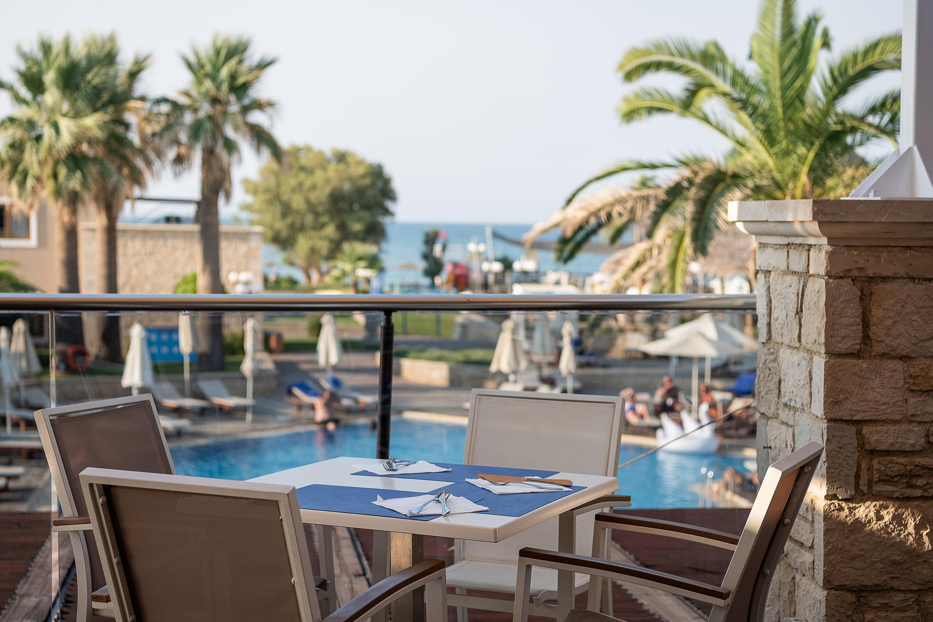A poolside area with lounge chairs, a table with a blue tablecloth, and umbrellas.