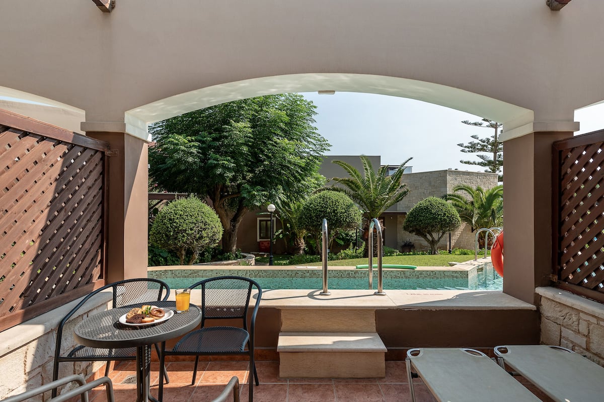 A patio area with a pool, outdoor seating, and a view of the surrounding greenery and buildings.