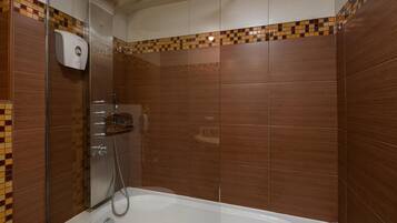 A modern bathroom with a glass-enclosed shower, a handheld showerhead, and a built-in toilet.