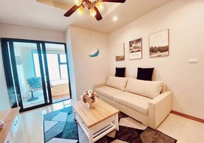 Relax in this inviting living room with a sofa, coffee table, and framed artwork, leading out to an outdoor space.