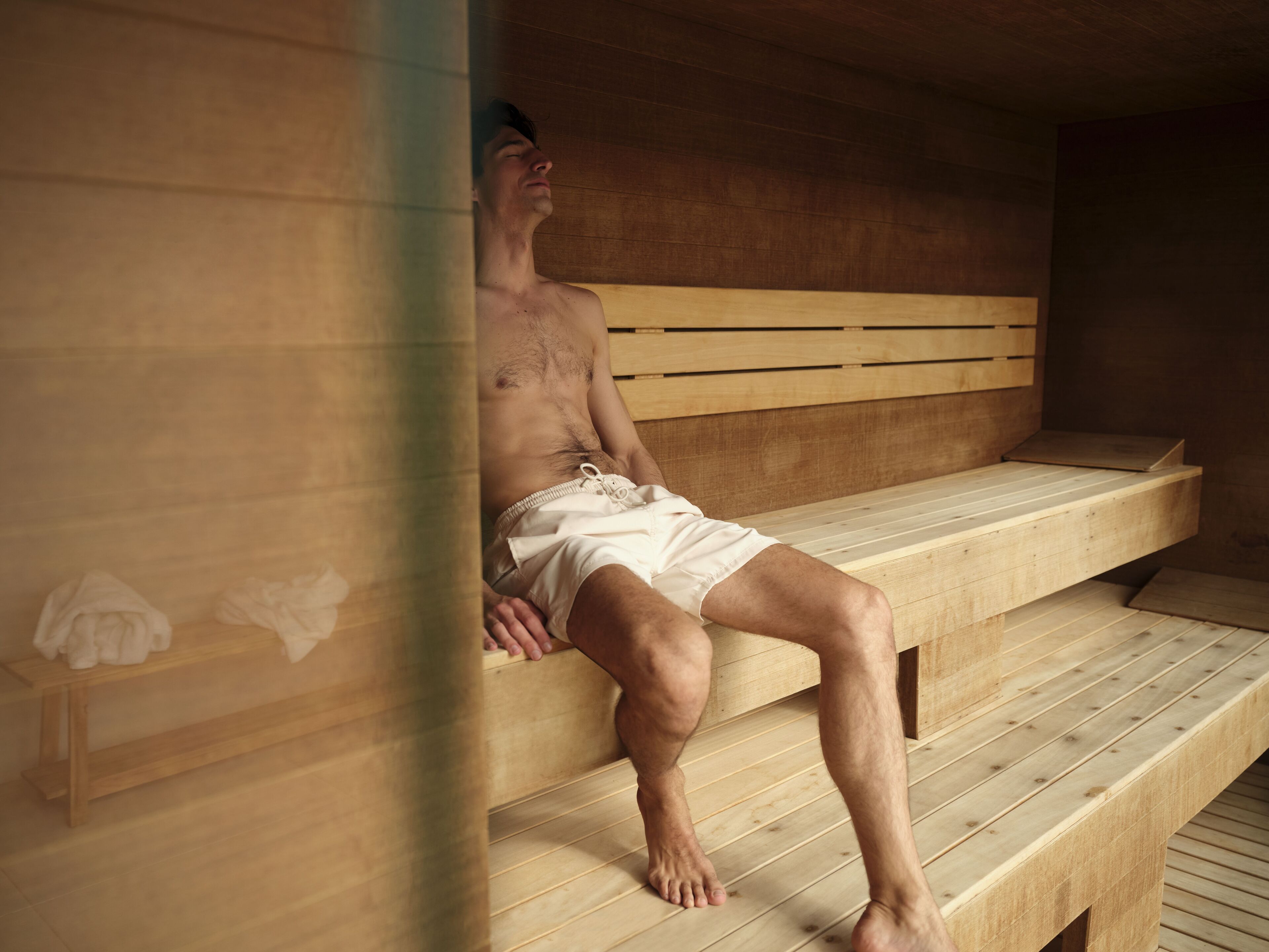 A wooden bench with a person sitting on it.