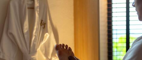 A massage therapy session in a room with a bed, a robe hanging on the wall, and a window with blinds.
