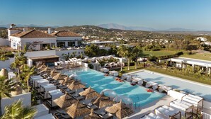 A resort with a large pool, sun loungers, and thatched umbrellas. - SO/ Sotogrande Spa and Golf Resort Hotel Costa del Sol (San Roque)