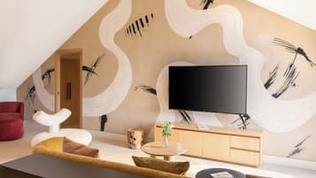 Una sala de estar moderna con un televisor de pantalla plana, una mesa redonda de centro y un sofá.
