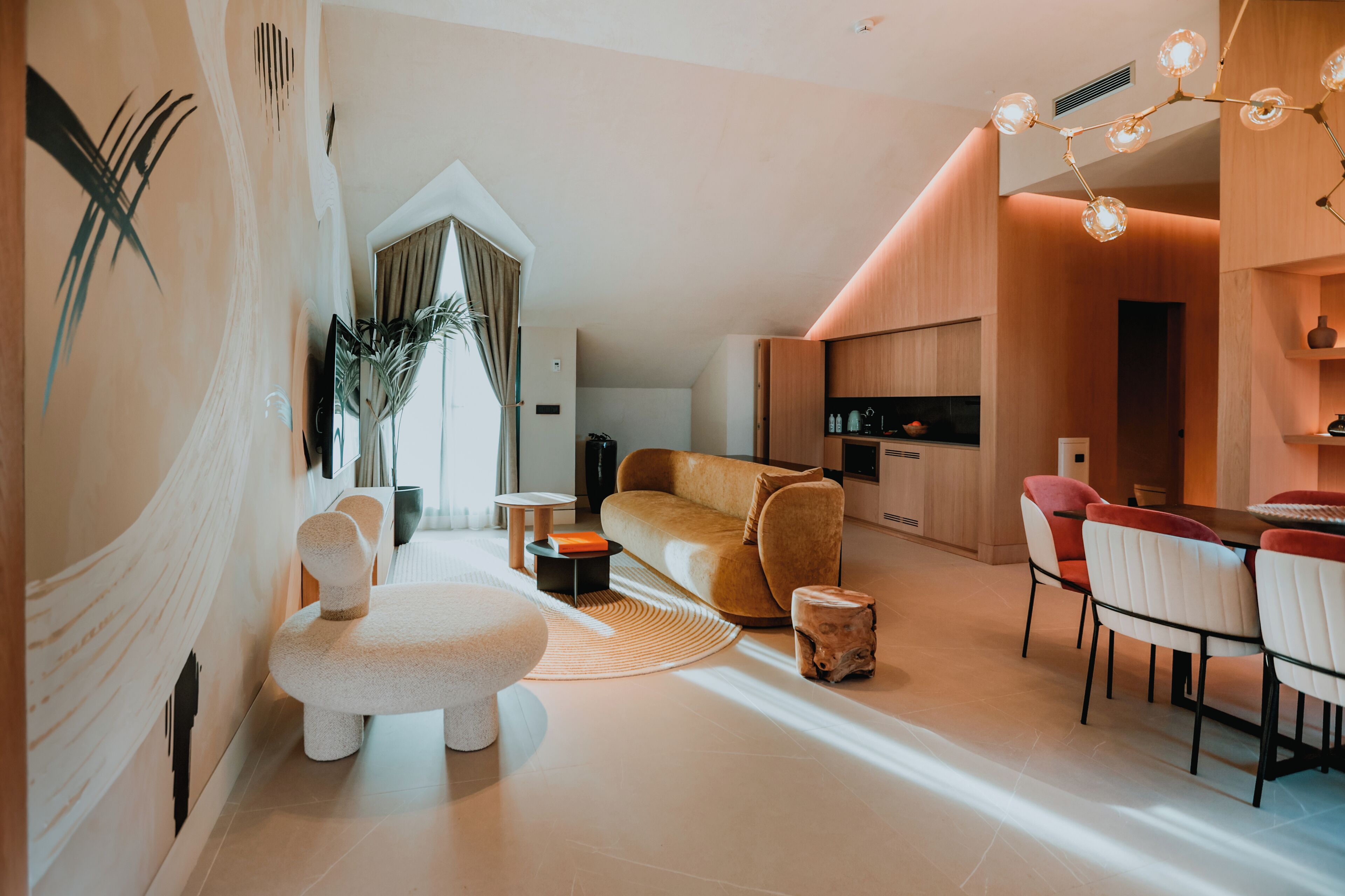 A modern living room with a sofa, chairs, a dining area, and a kitchen.