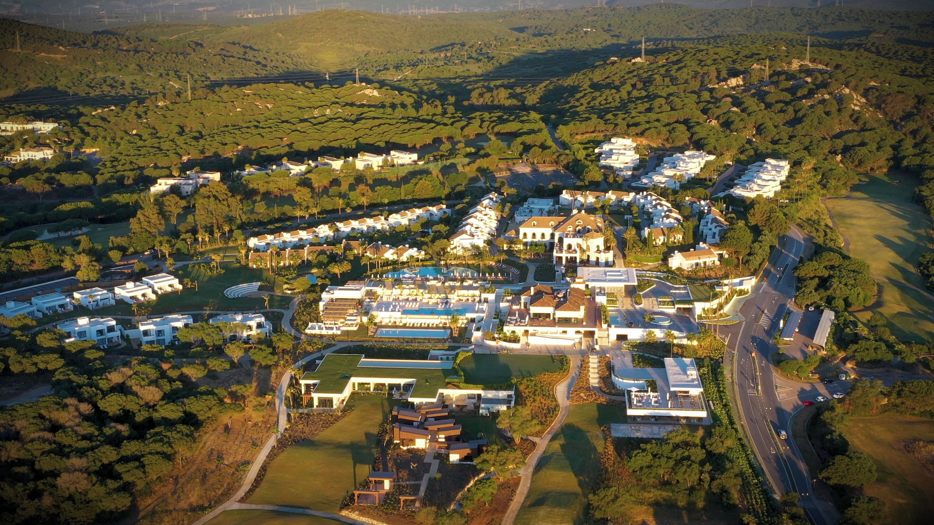 Vista aérea de una zona residencial con casas modernas, una piscina central y céspedes bien cuidados.