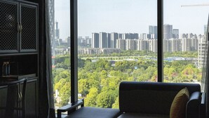 A room with a large window offering a view of a cityscape and greenery. - Sofitel Hangzhou Yingguan Hotel (Hangzhou)