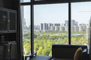 A room with a large window offering a view of a cityscape and greenery. - Sofitel Hangzhou Yingguan Hotel (Hangzhou)