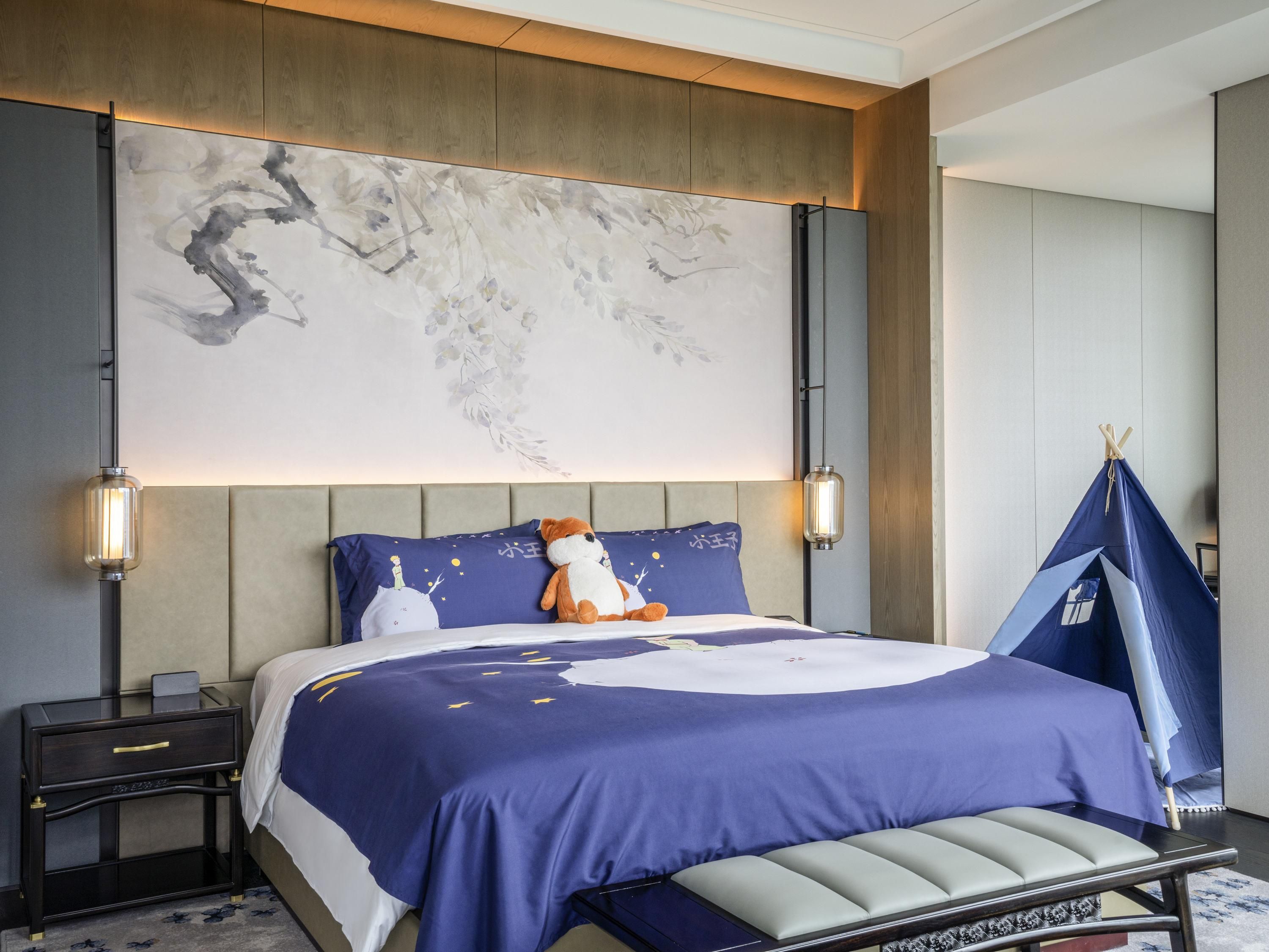 A modern bedroom with a large bed, a nightstand, a decorative wall, and a tent-like structure.