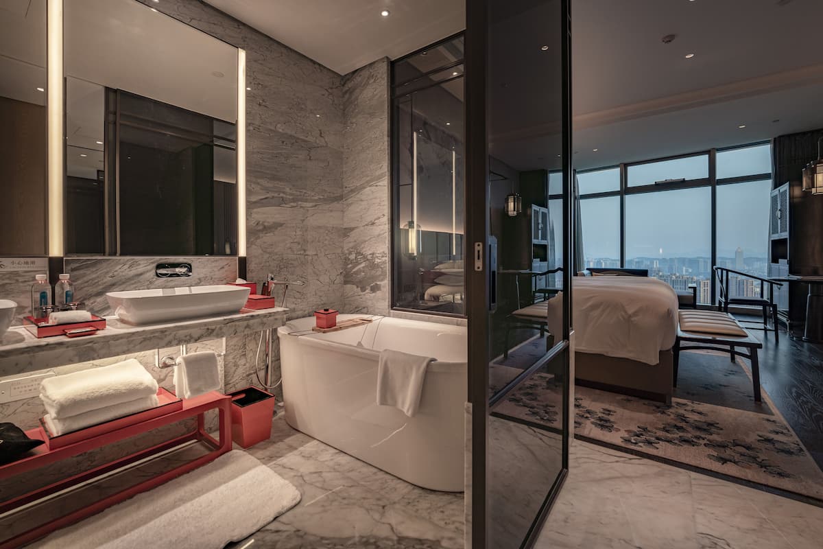 Een moderne badkamer met een grote spiegel, een witte wastafel en een vrijstaand bad.