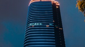 A modern hotel with a curved facade, illuminated signage, and a prominent entrance with a glass facade. - Sofitel Hangzhou Yingguan Hotel (Hangzhou)