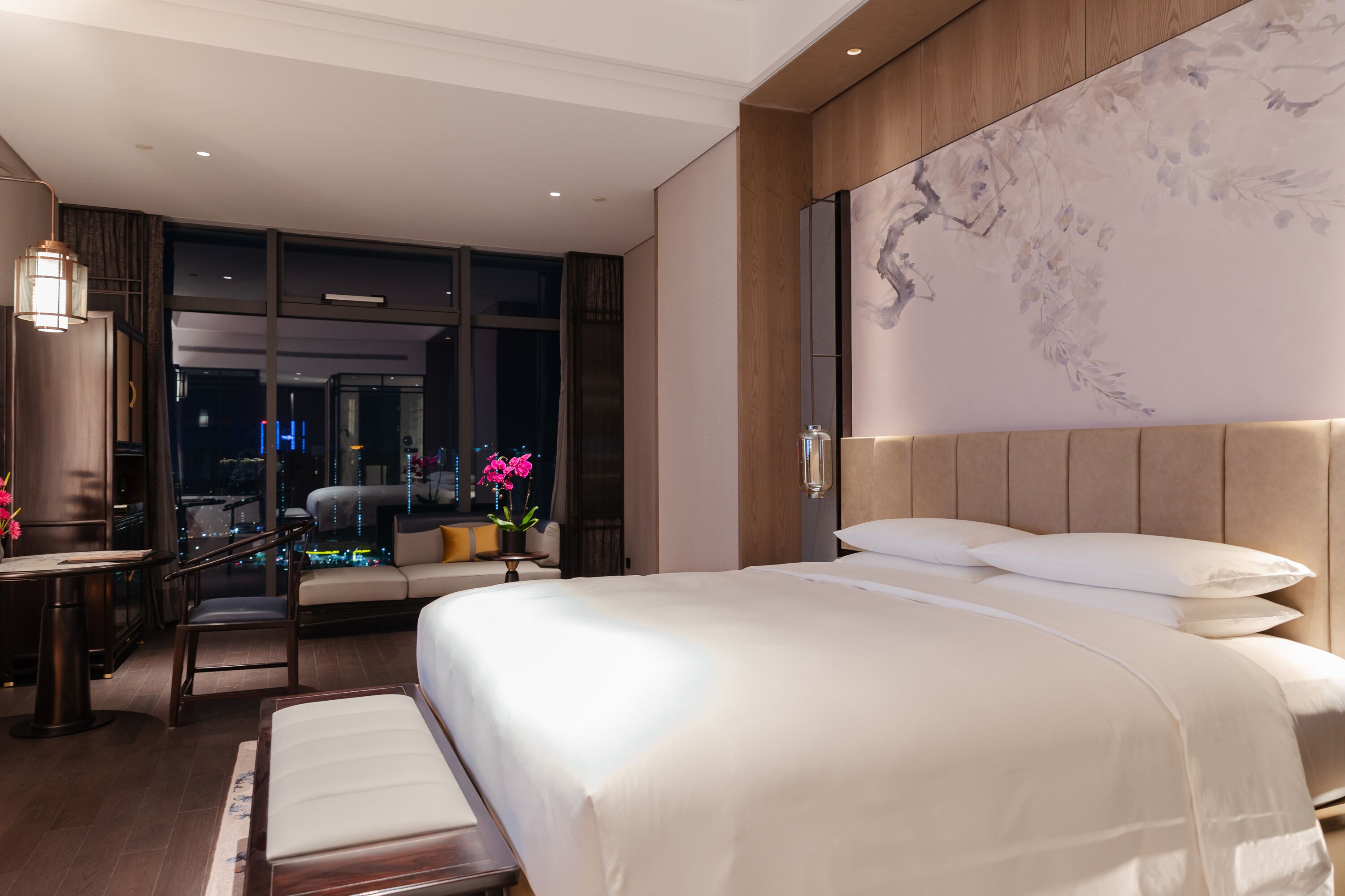 Una habitación de hotel moderna con una cama grande, un escritorio y una zona de estar.