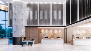 A modern hotel lobby with marble reception desks, a large vertical panel design, and a cityscape mural. - Sofitel Hangzhou Yingguan Hotel (Hangzhou)