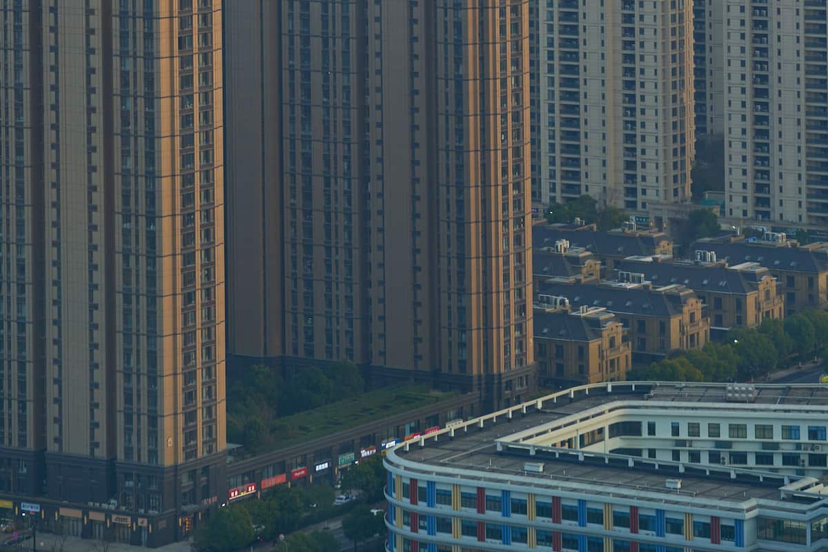 Een hoog woongebouw met meerdere verdiepingen, een opvallende centrale toren en een omliggend stadslandschap met andere gebouwen.