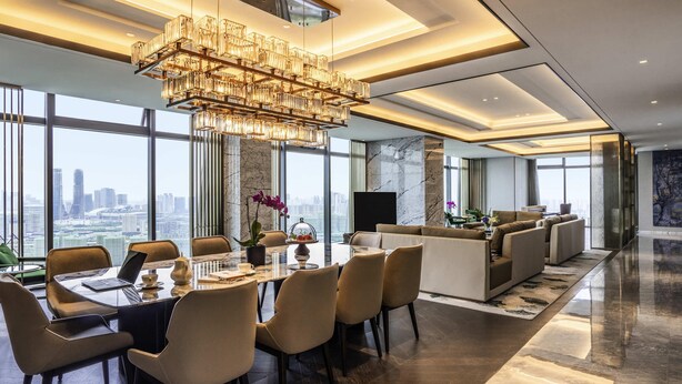 A modern hotel dining area with a large table, chairs, a chandelier, and a city view. - Sofitel Hangzhou Yingguan Hotel (Hangzhou)