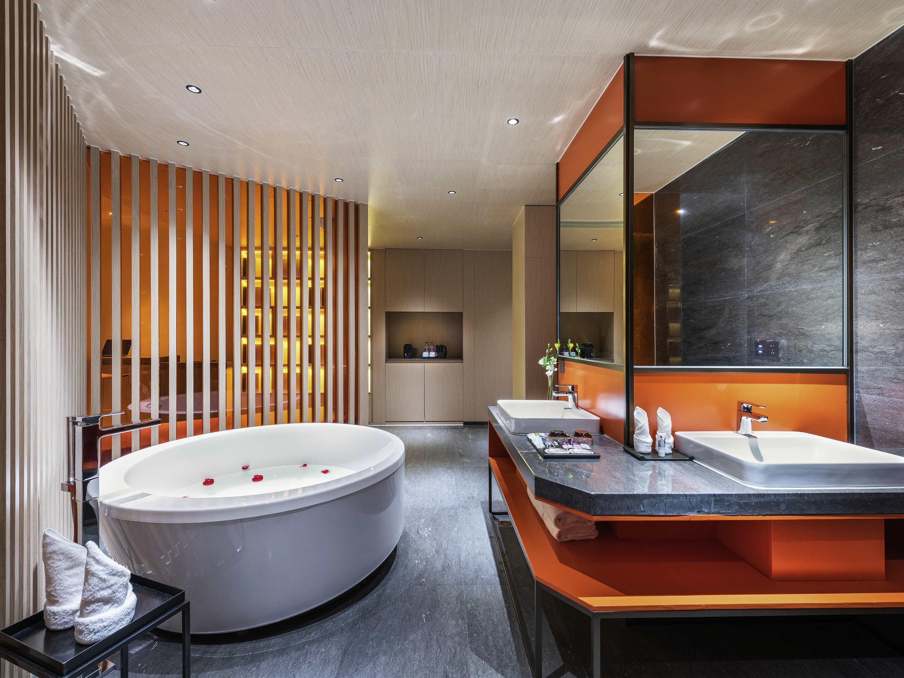 A modern bathroom with a freestanding bathtub, two sinks, and a large mirror.