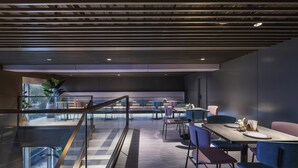 A modern dining area with a glass railing, wooden flooring, and contemporary furniture.