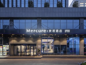 A Mercure hotel with a modern facade, large windows, and a well-lit entrance.