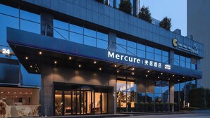 A hotel entrance with a sign reading 'Mercure' and a 24-hour service sign.