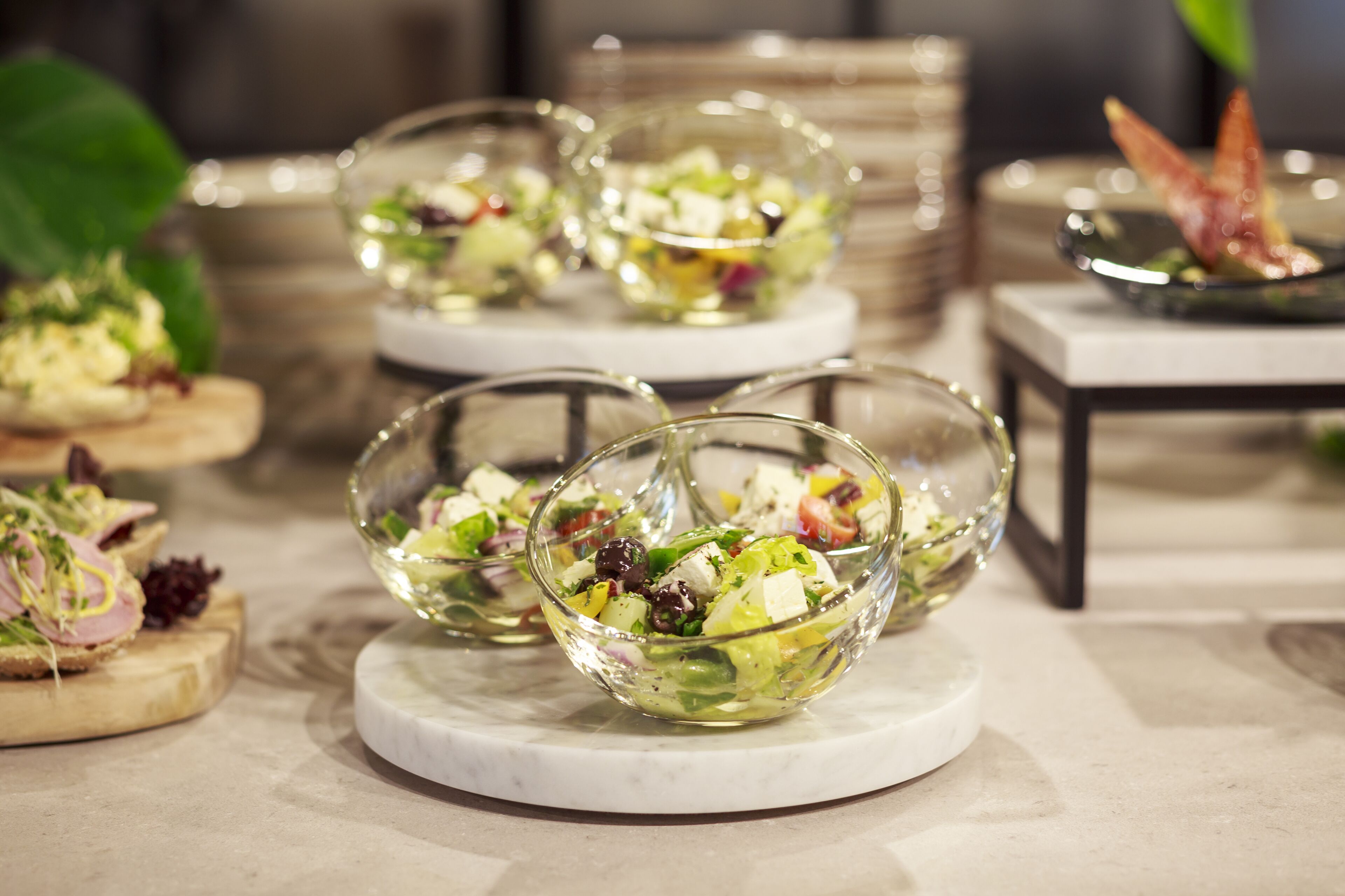 Three glass bowls of salad on a marble table.