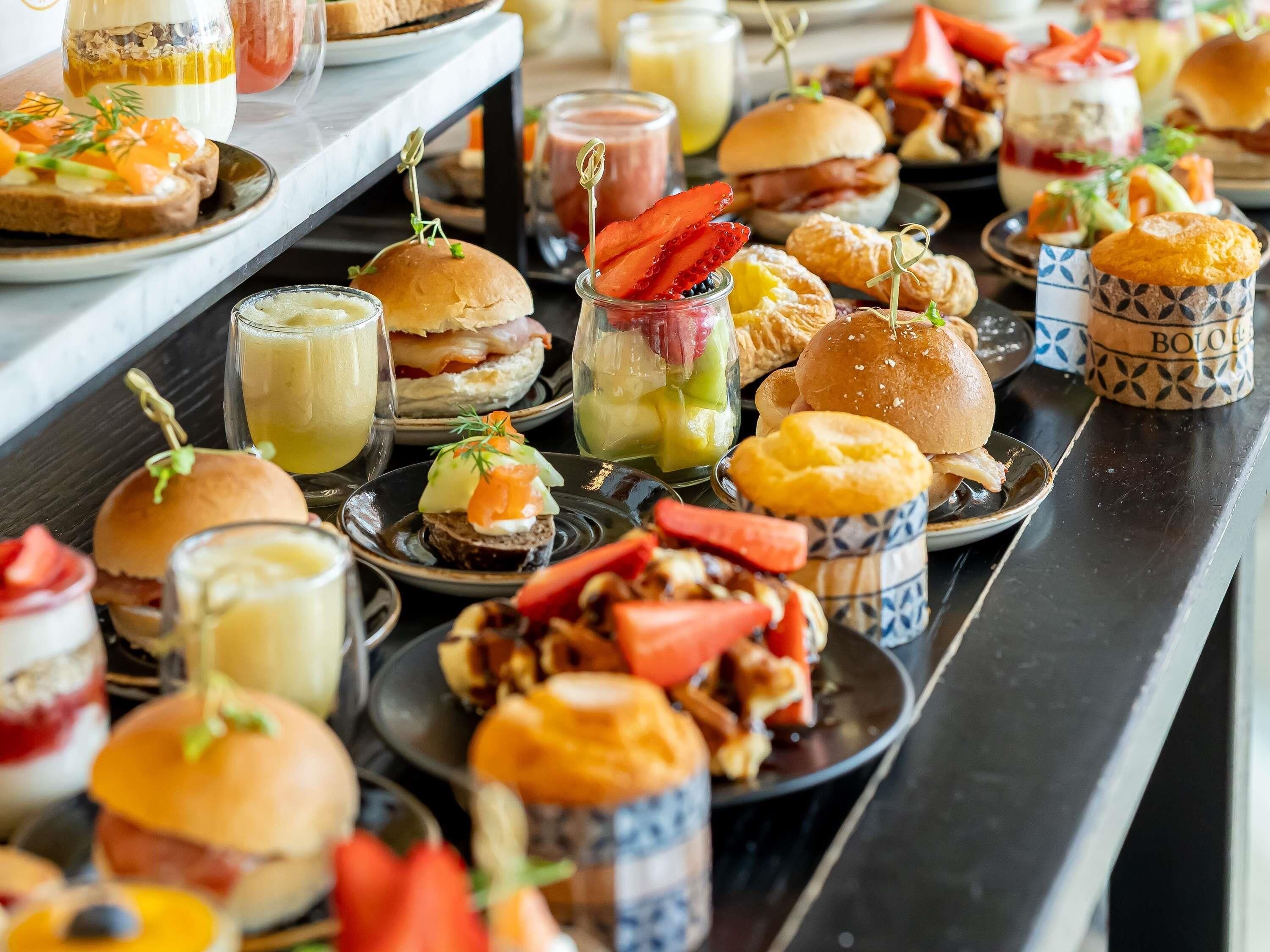 Une variété d’aliments, notamment des sandwichs, des pâtisseries et des boissons, disposés sur une table.