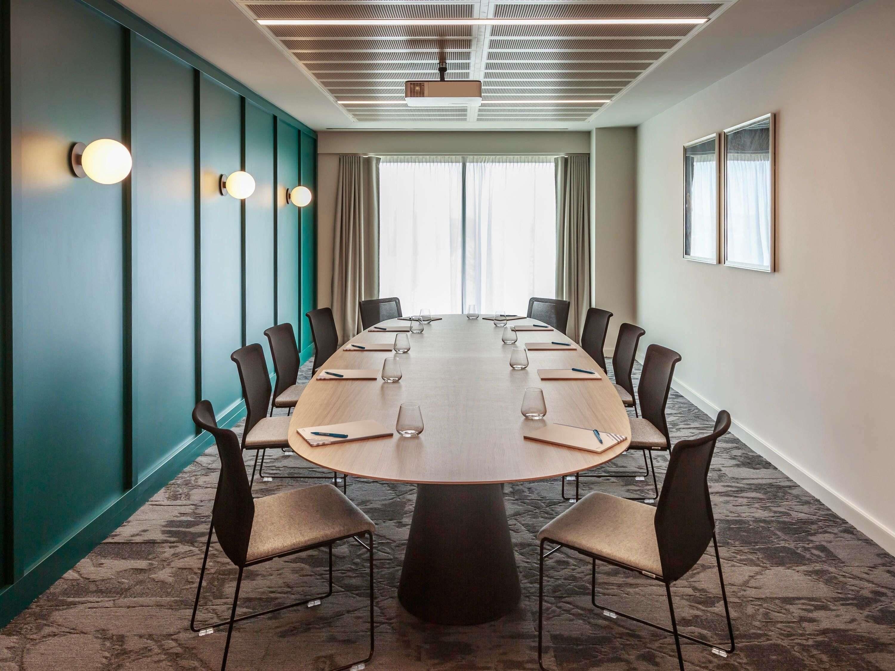 A conference room with a long table, chairs, and a ceiling projector.