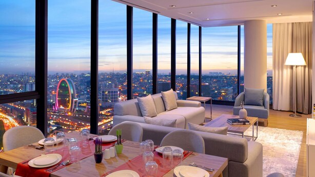 A modern dining area with a city view, a sofa, and a lamp. - Mövenpick Living Istanbul West (Istanbul)